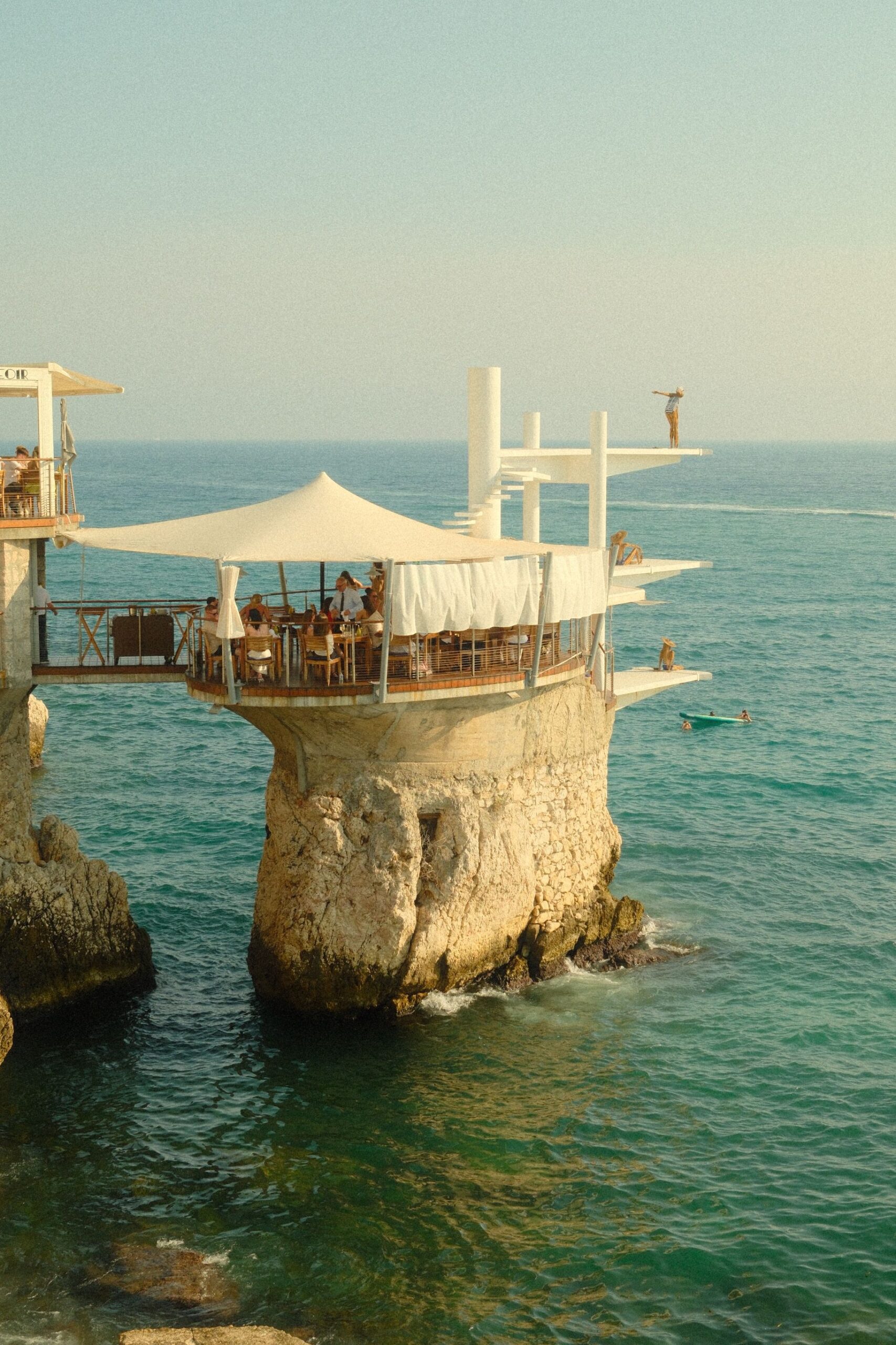 A scenic view of a cliffside cafe over the azure Mediterranean Sea in sunny France.